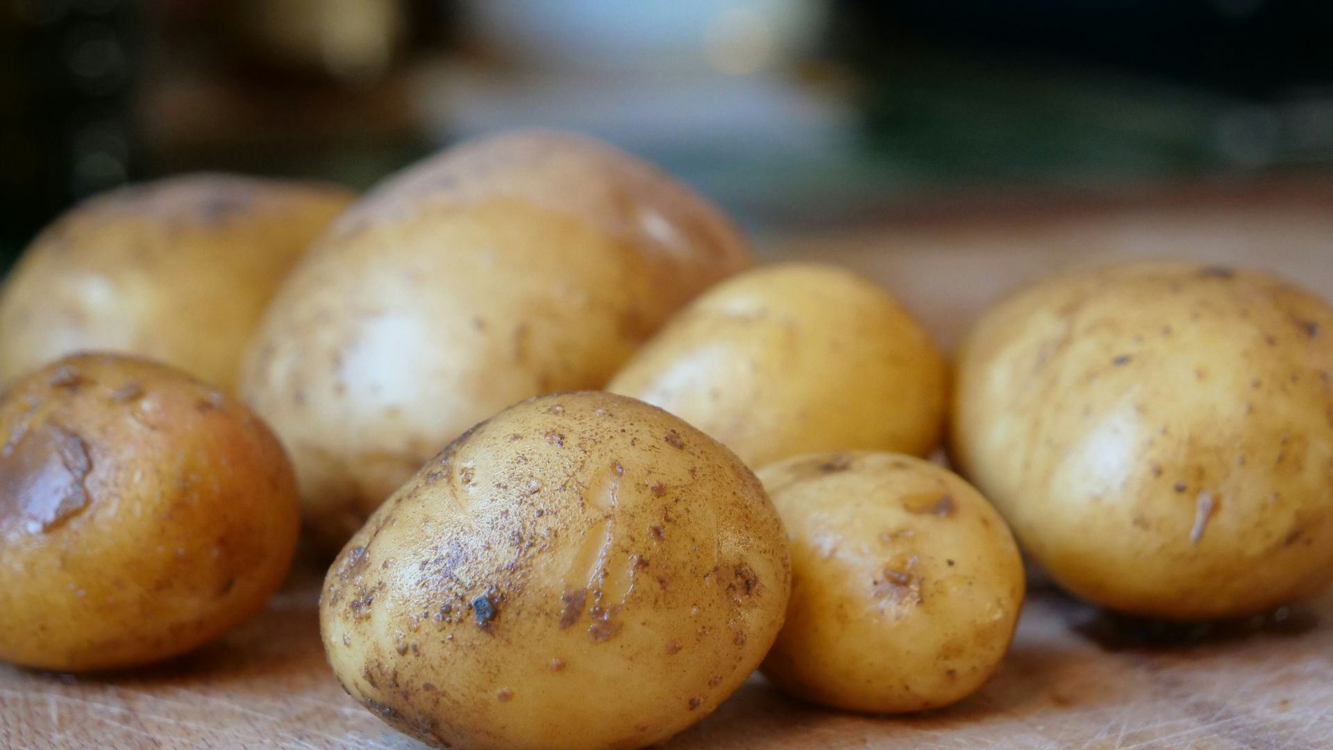 Several raw potatoes resting on a wooden surface