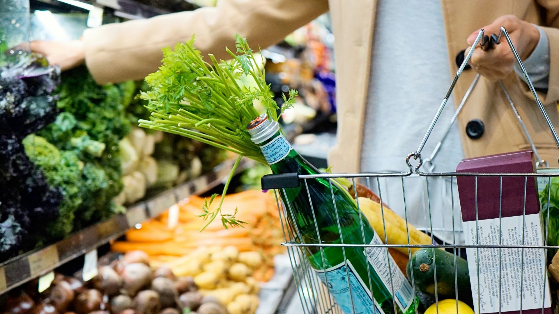 woman in white coat holding green shopping cart