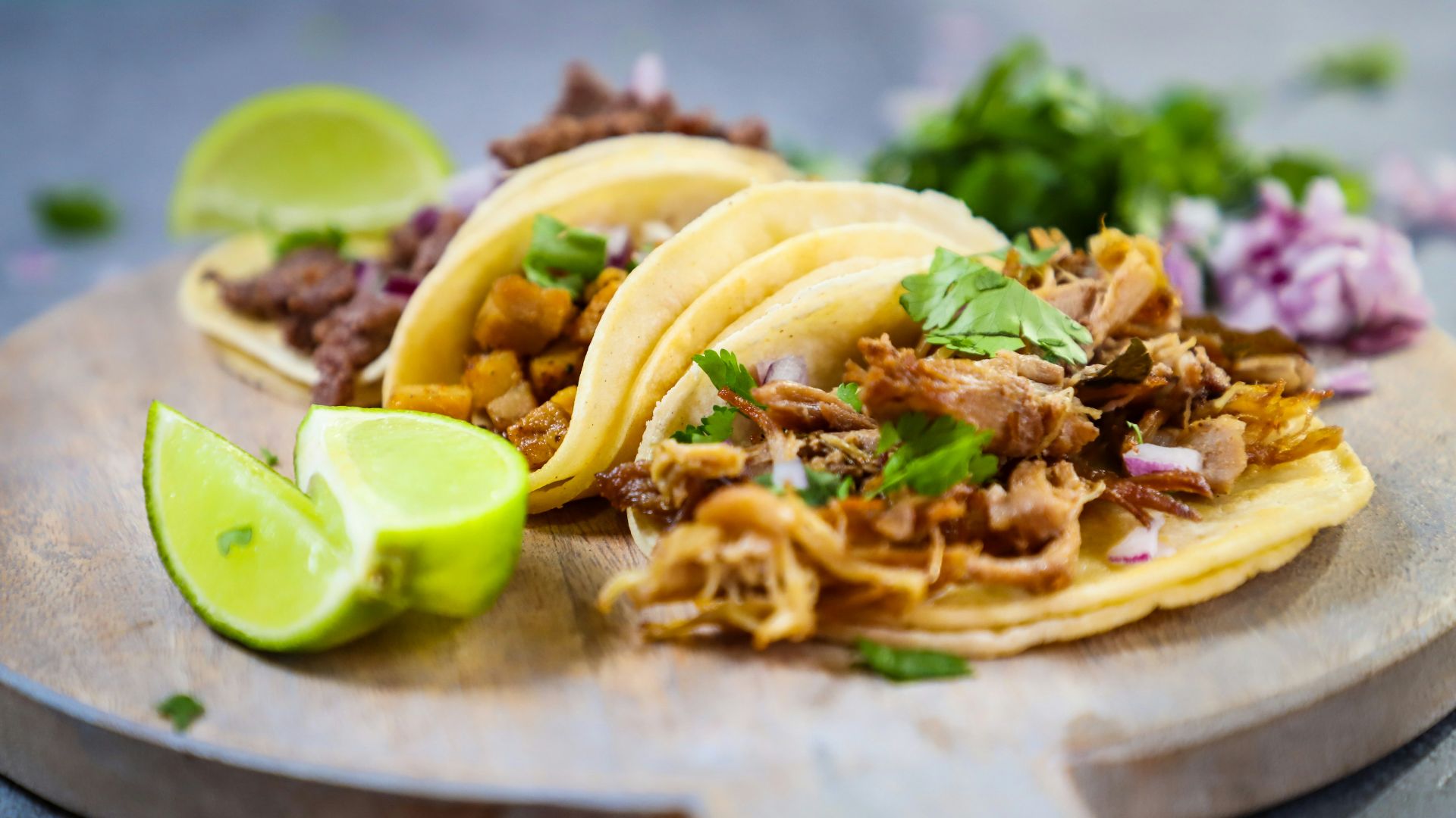 a wooden plate topped with three tacos and a lime