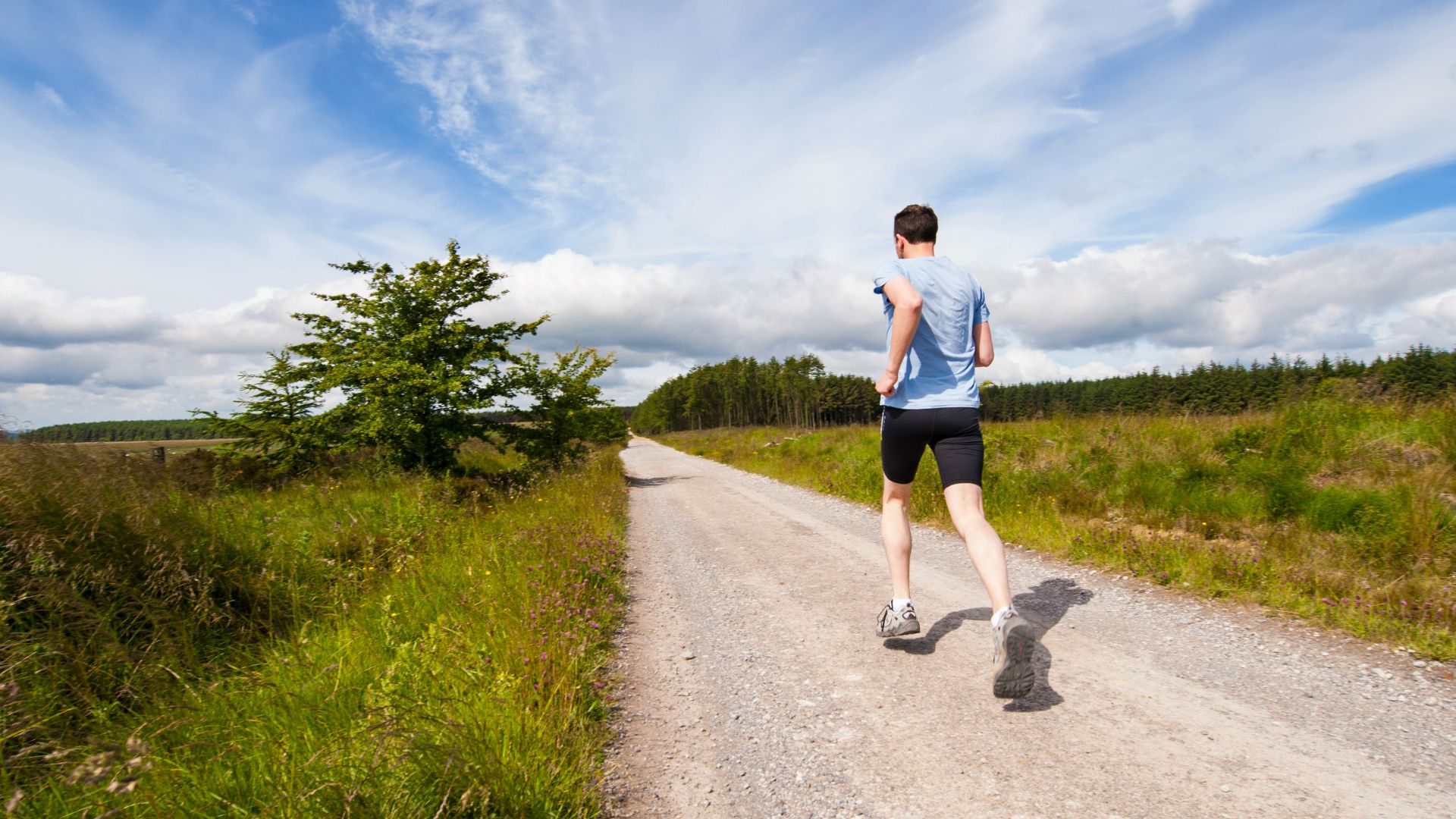 man running on road near grass field