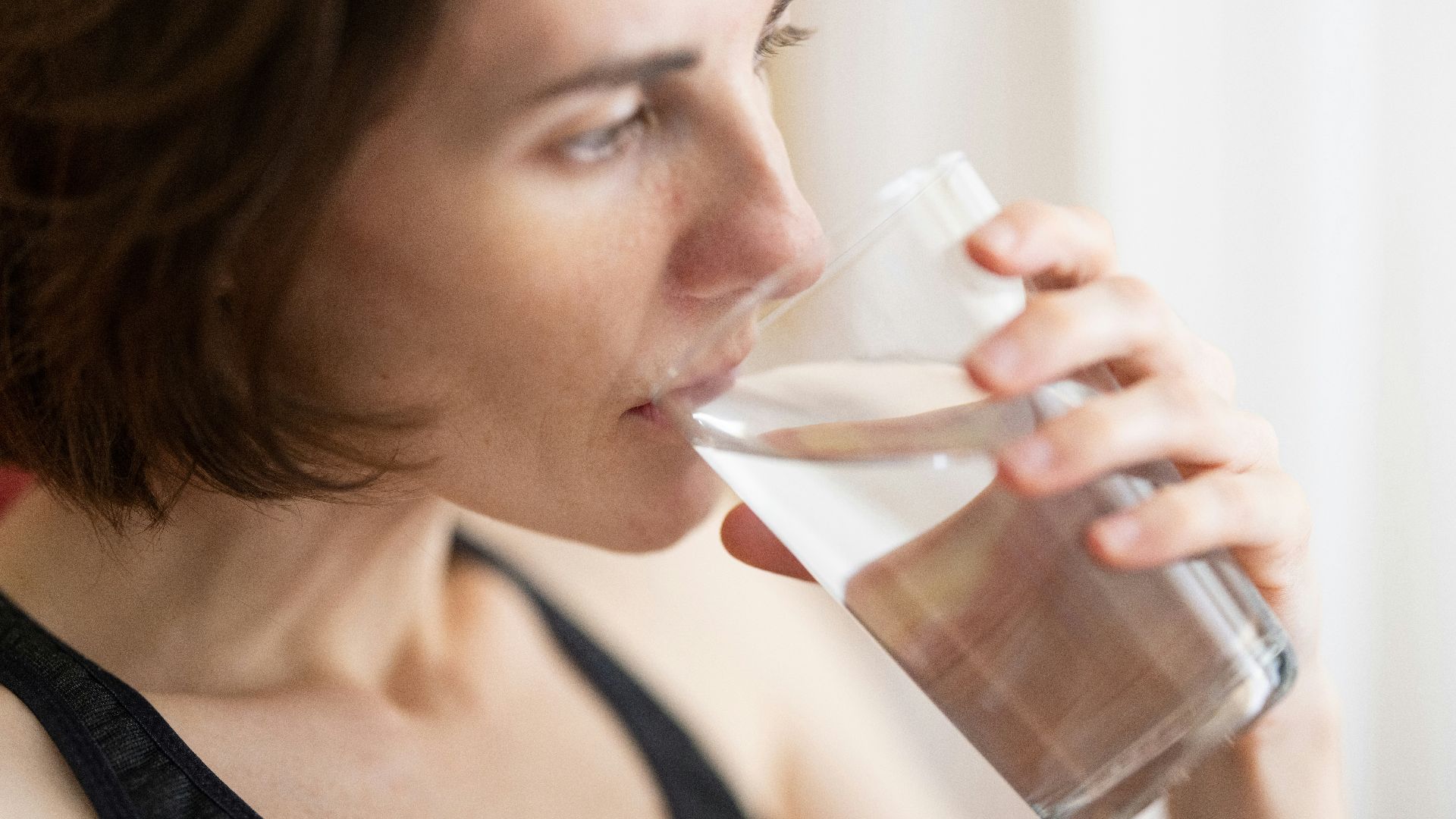 woman in black tank top drinking water