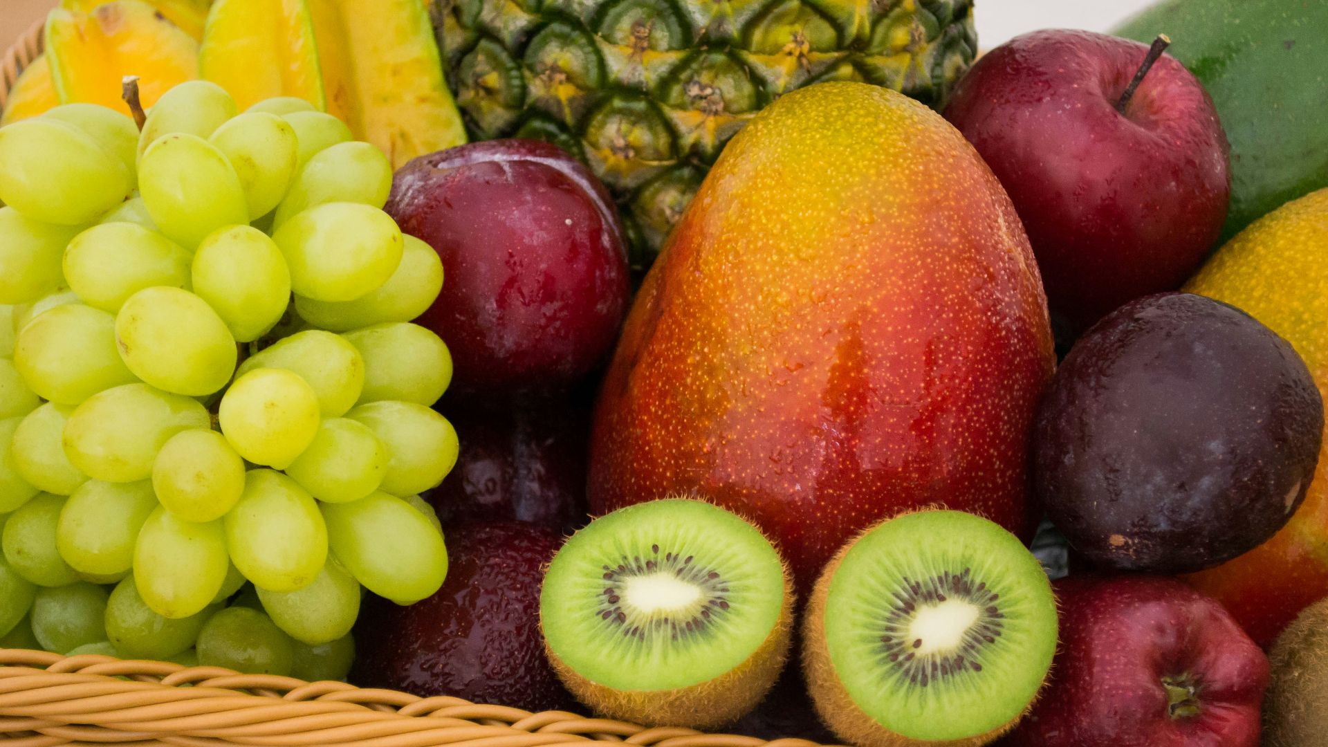 red apple fruit beside green apple and yellow fruit on brown woven basket