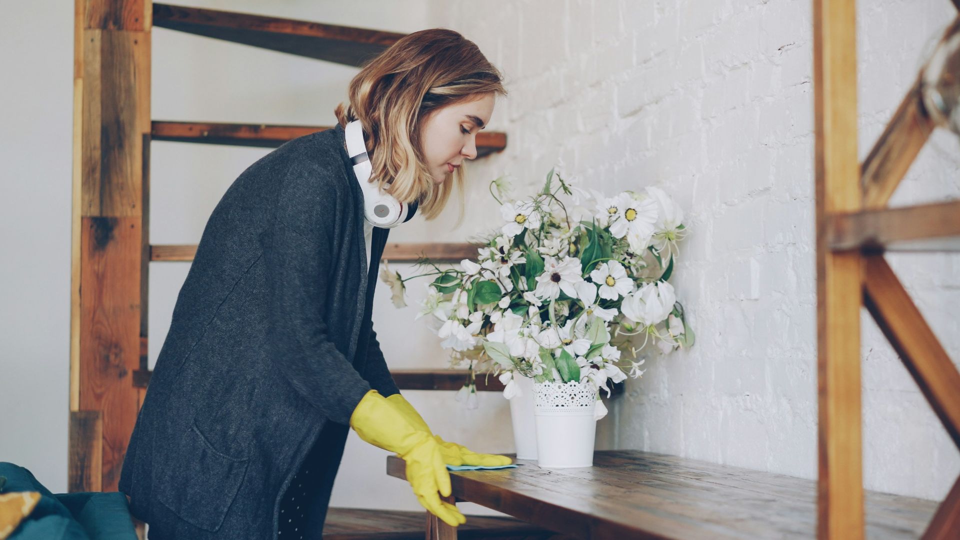 Woman in yellow gloves cleaning a shelf