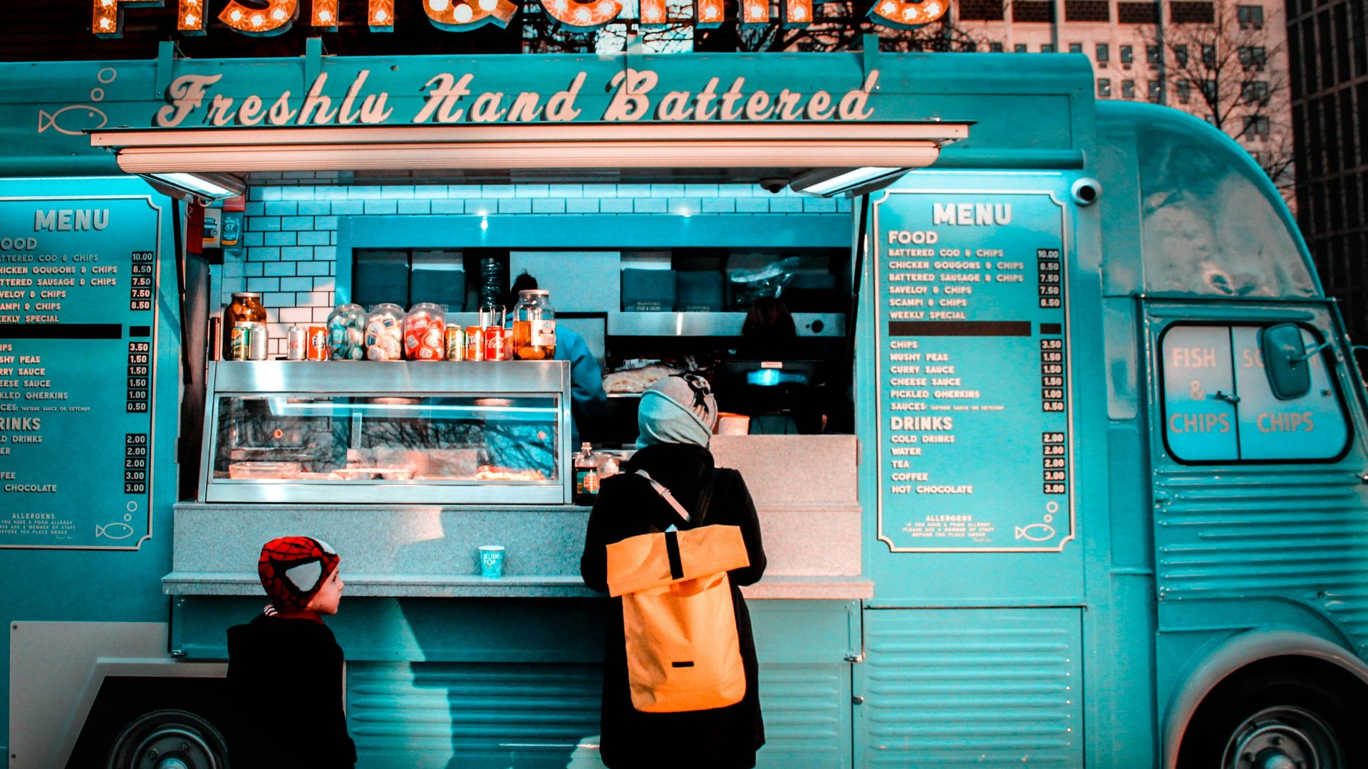 woman in brown coat standing in front of food stall