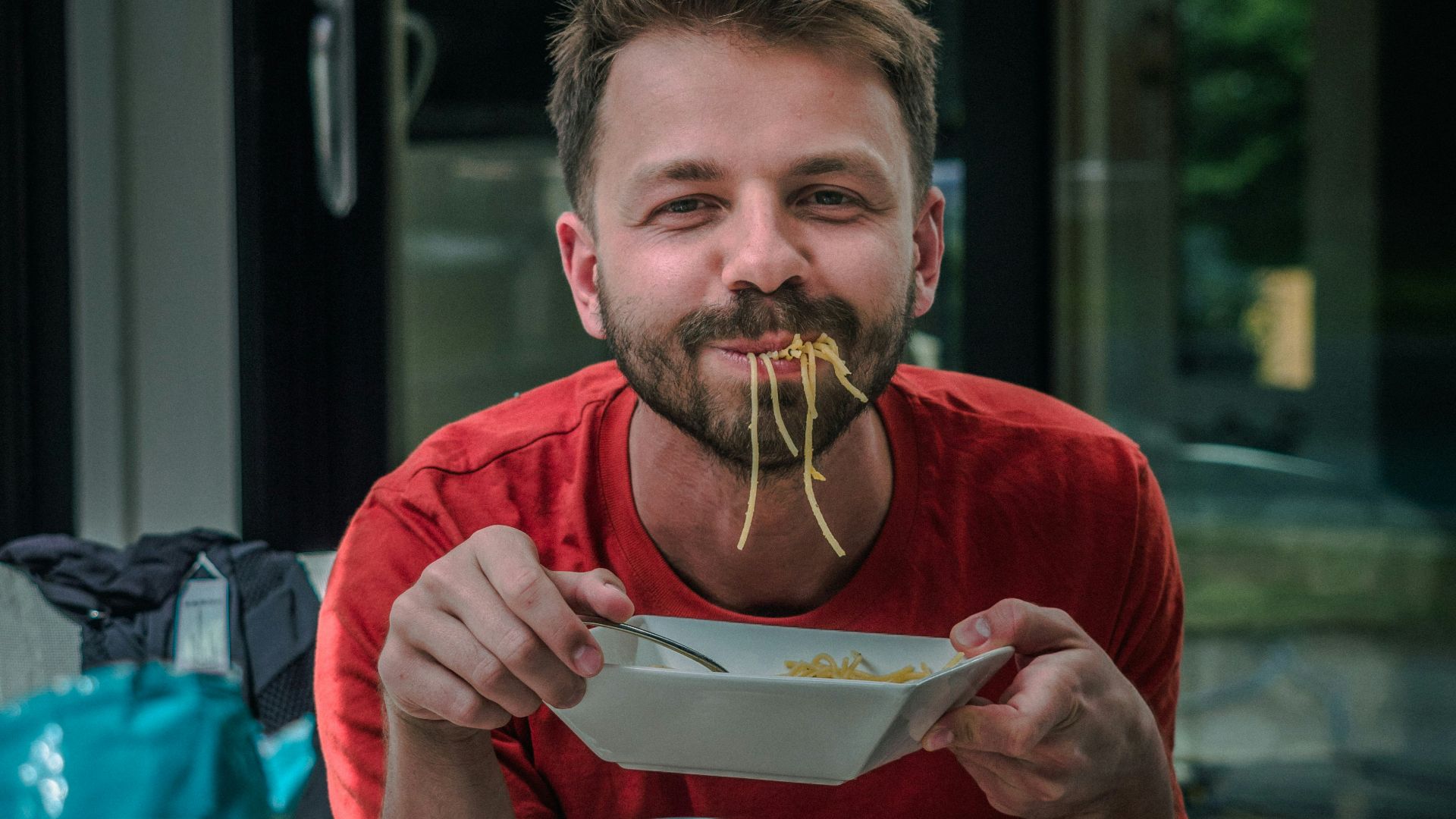 man in red crew neck t-shirt holding white and red labeled can