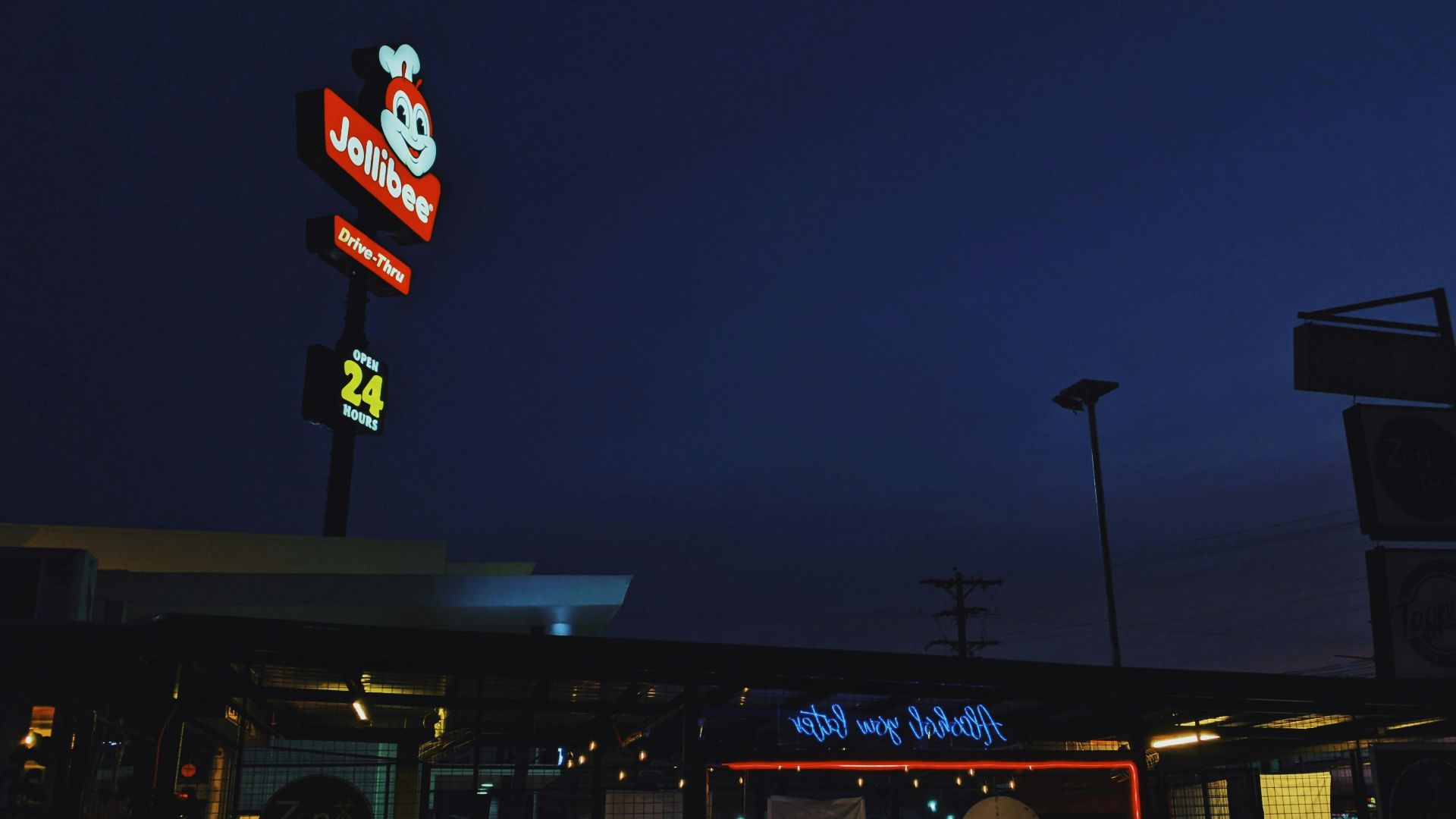 a restaurant at night with neon signs and a dark sky