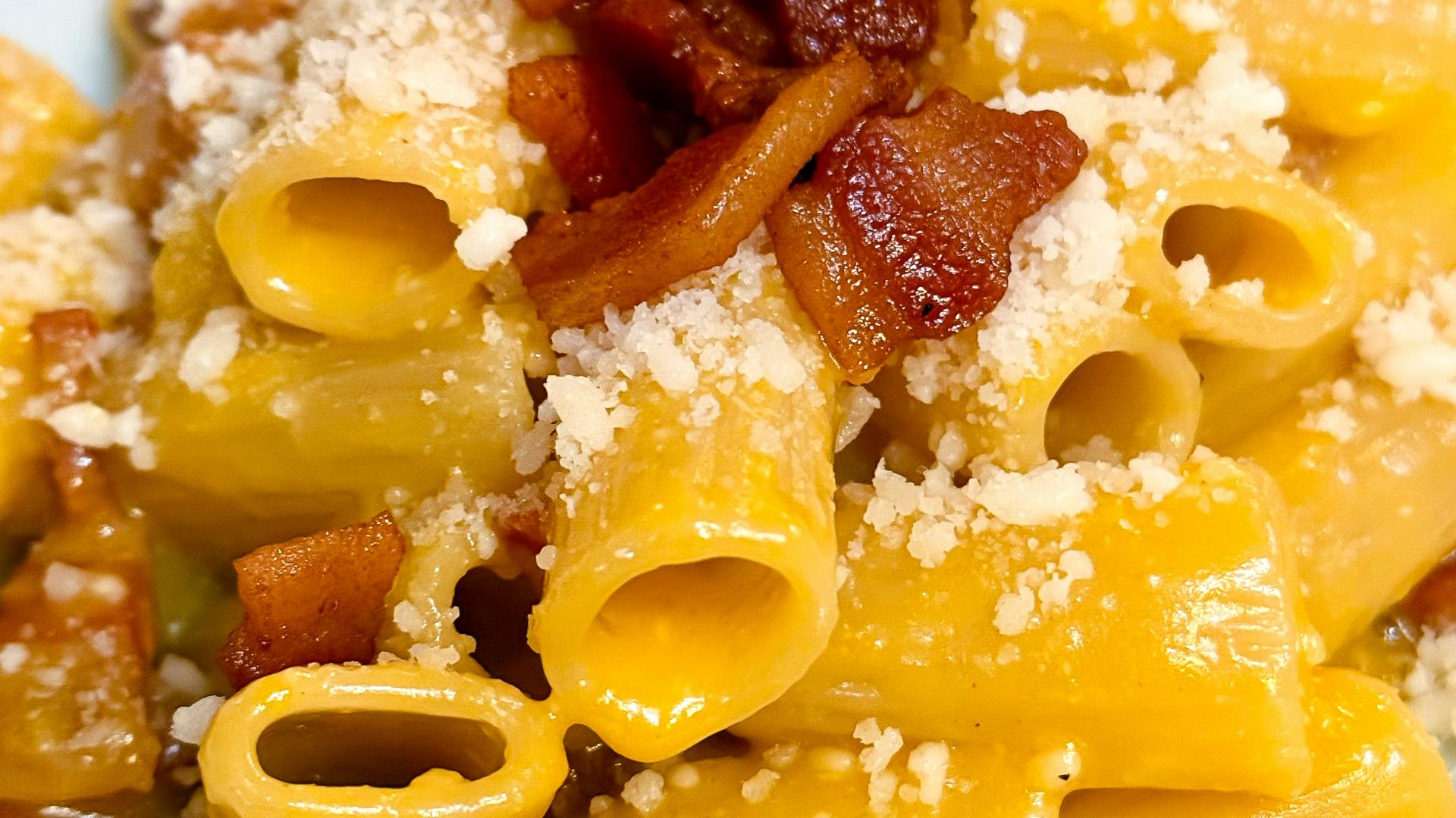 A white plate topped with pasta and bacon