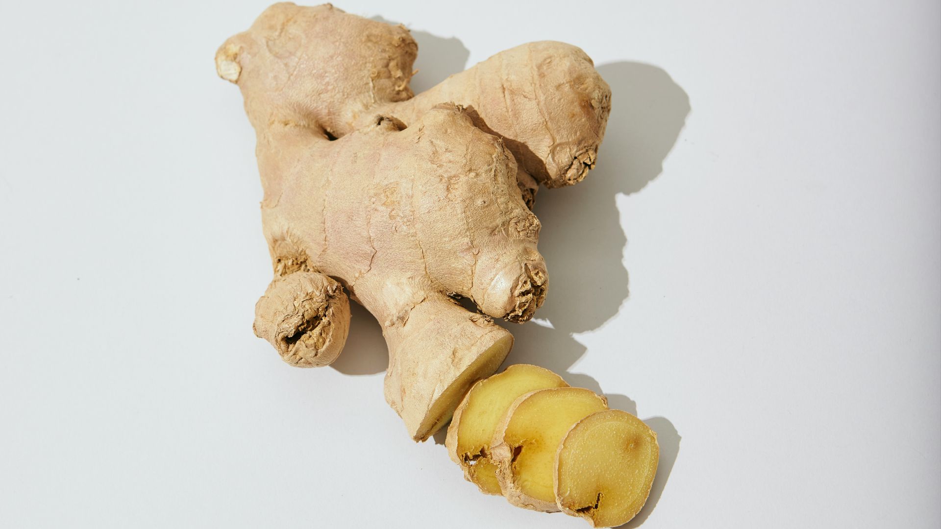 a ginger root and a piece of ginger on a white surface