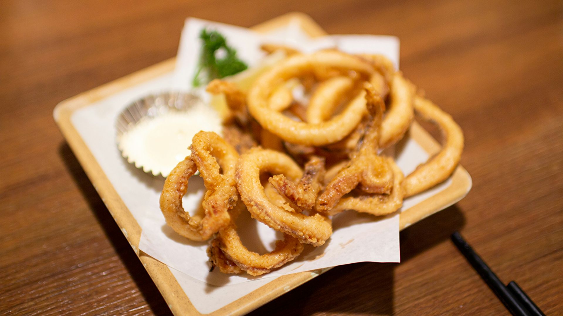 Here is a caption: fried calamari served with dipping sauce.