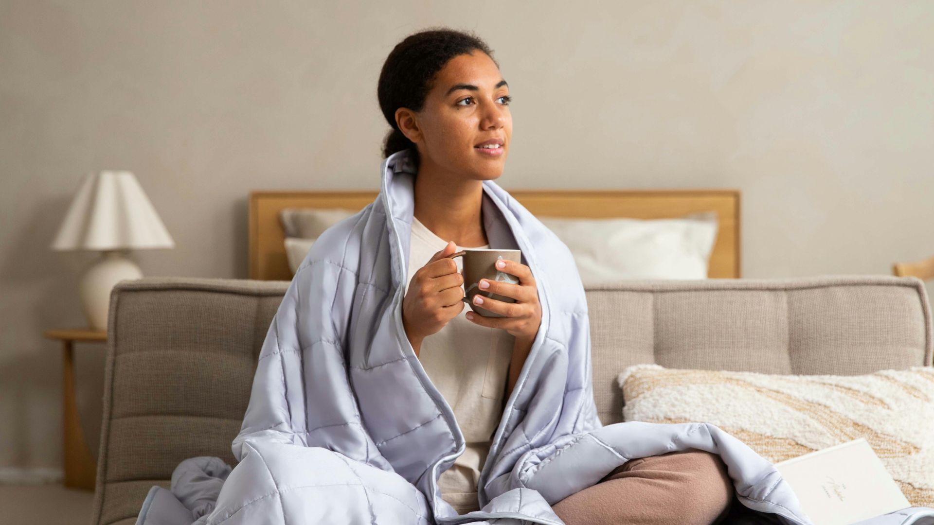 a woman sitting on a couch holding a cup of coffee