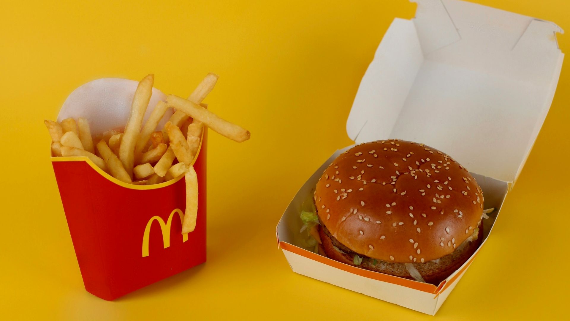 a mcdonald's hamburger and french fries on a yellow background