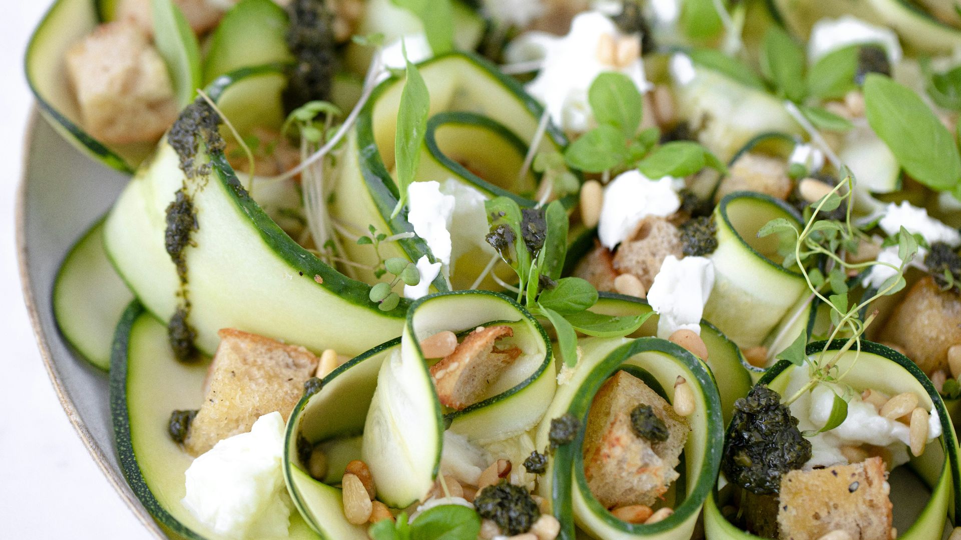 a plate of zucchini, spinach, and goat cheese salad