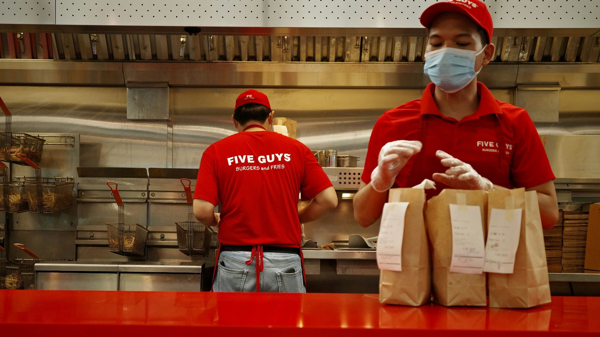 A man wearing a face mask standing behind a counter