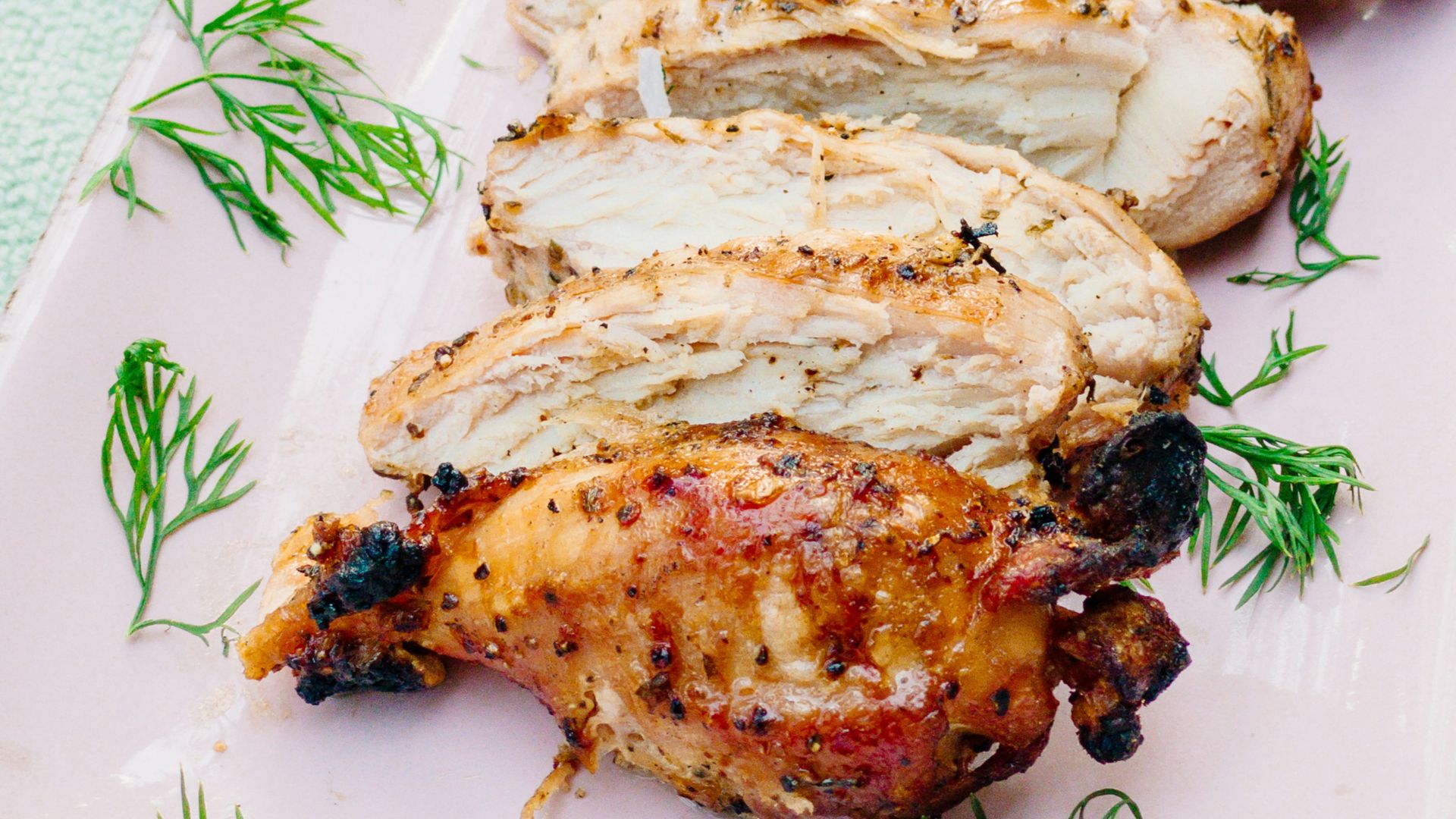 a pink plate topped with meat covered in sauce