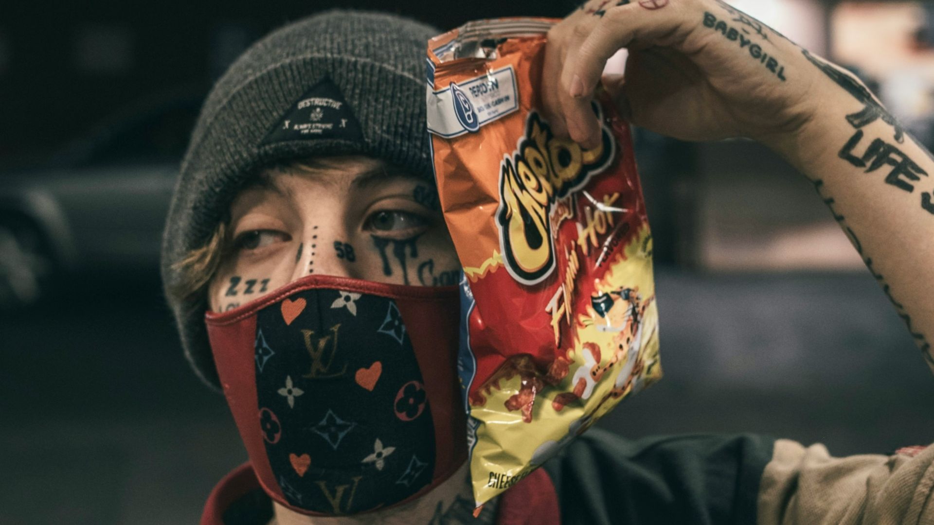 man in black button up shirt wearing black knit cap holding red and white mask