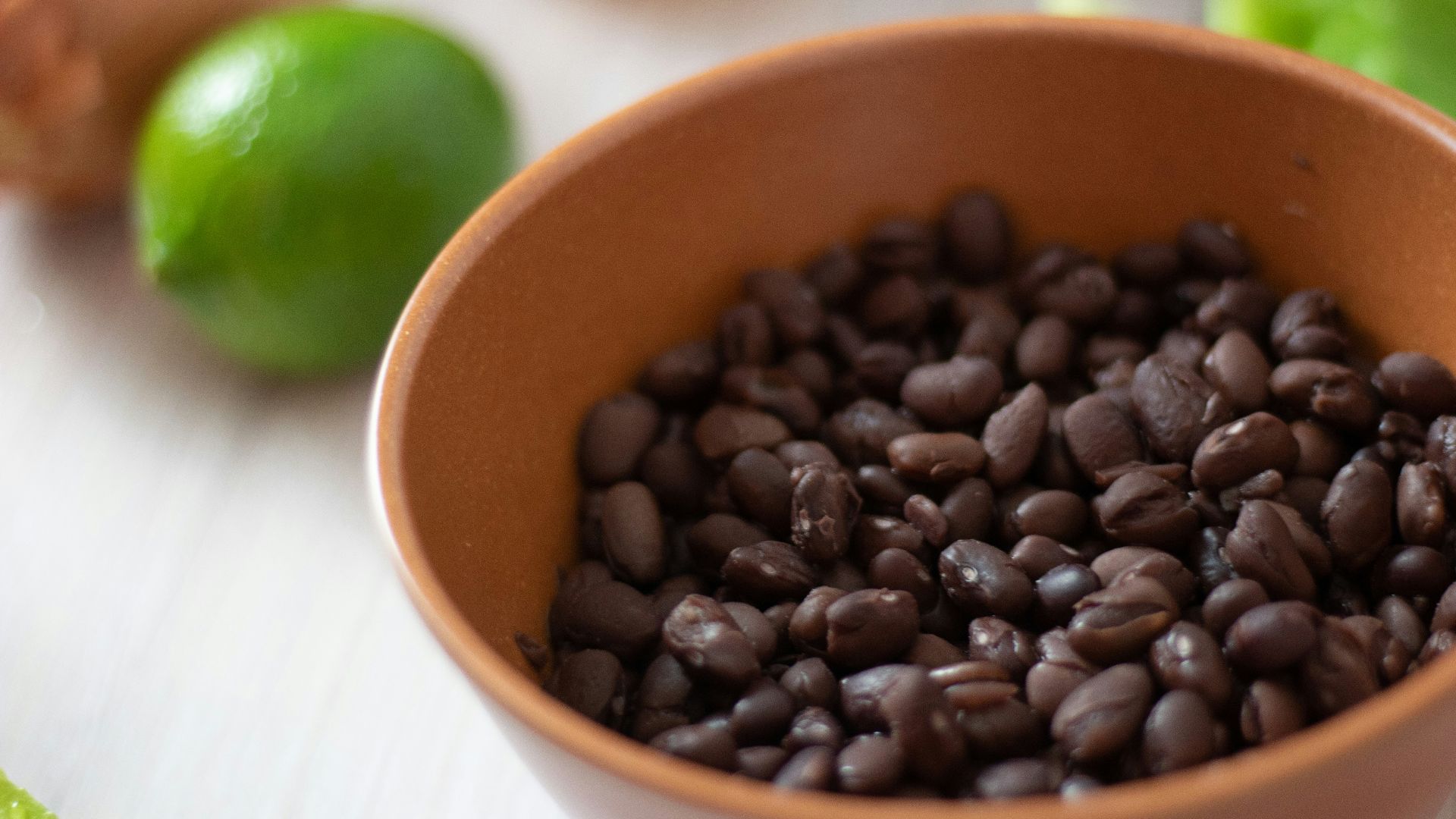 a bowl filled with black beans next to limes