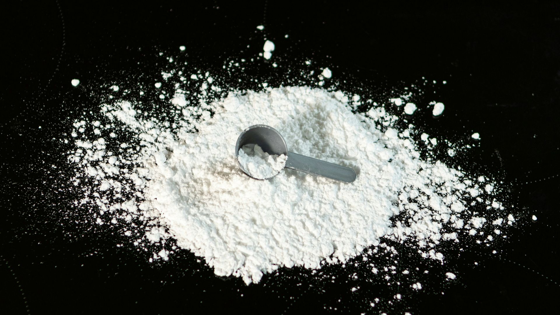 a scoop of powder next to a scoop of sugar