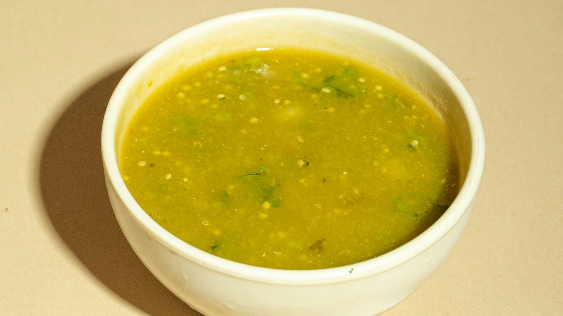 A white bowl filled with green soup on top of a table