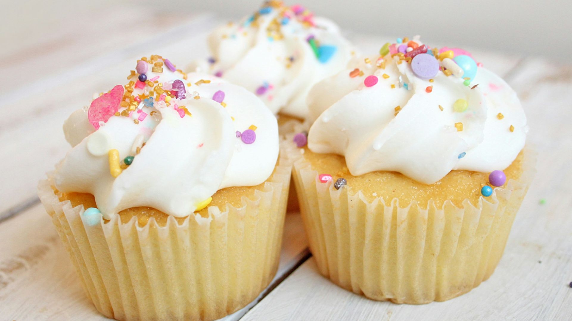 three cupcakes on white wood
