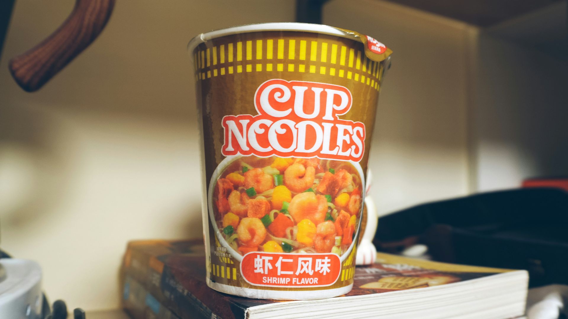 a cup of noodles sitting on top of a stack of books