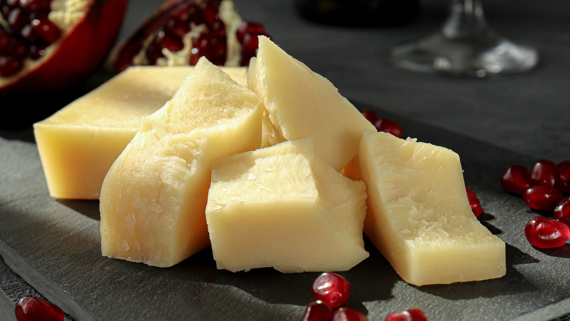sliced cheese on black plate beside wine glass
