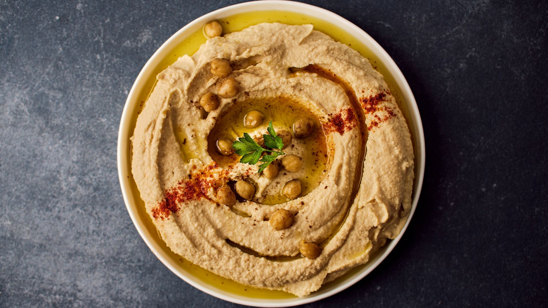 a bowl of hummus with a garnish on top