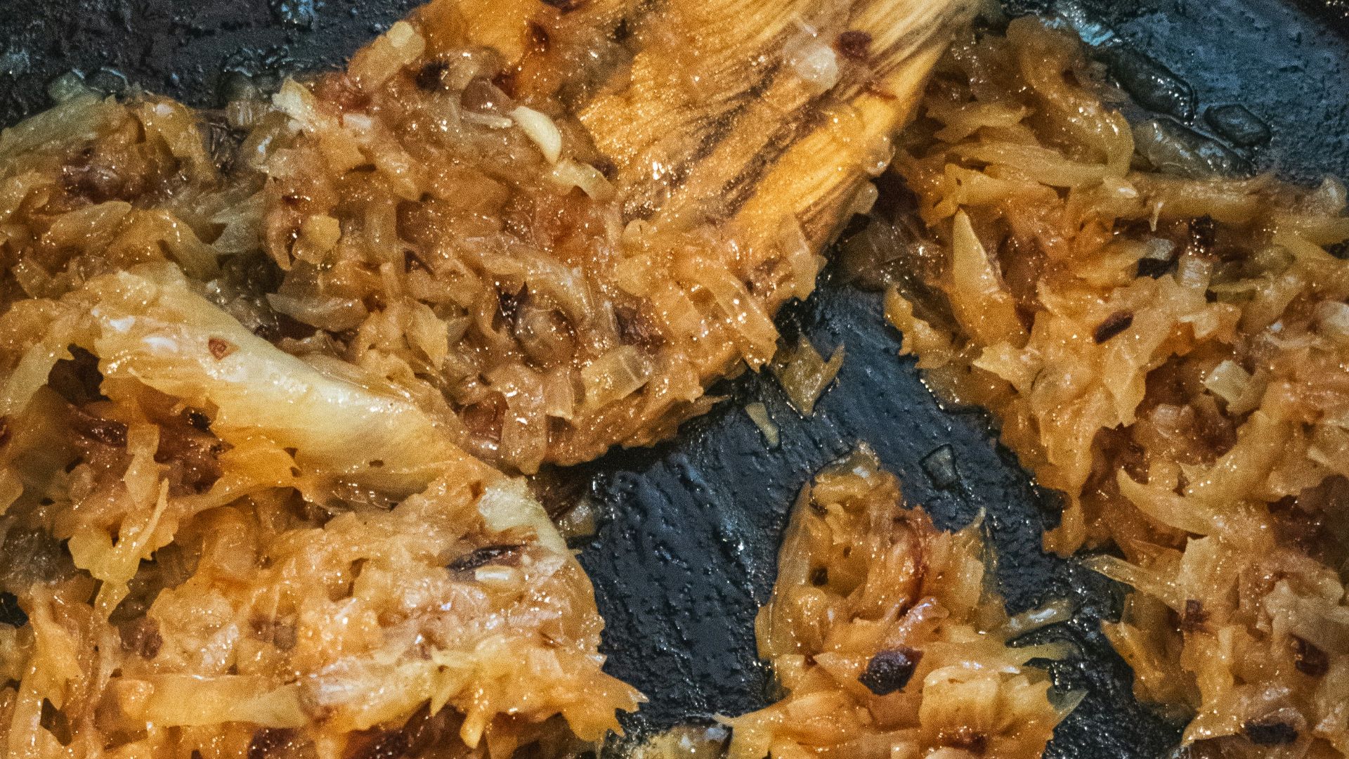 a frying pan filled with fried food and a wooden spoon