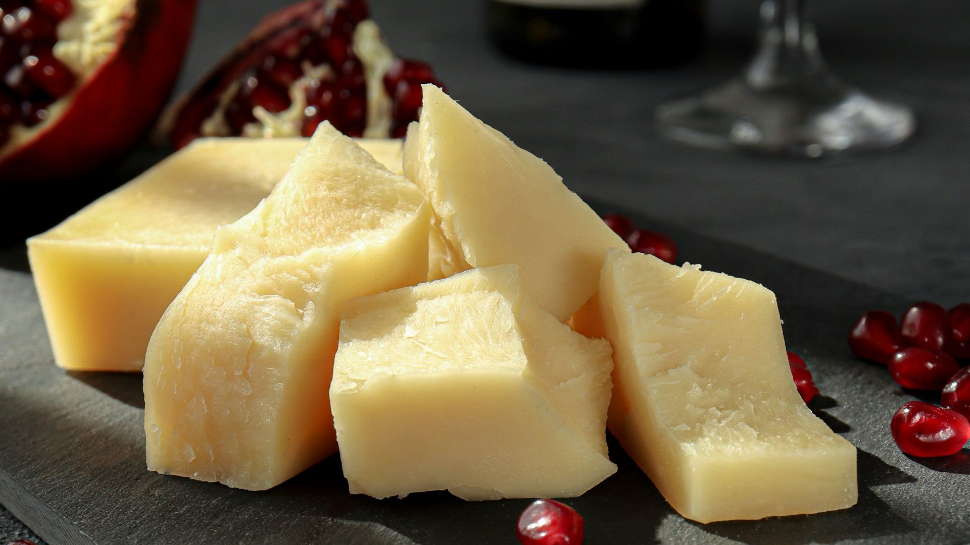 sliced cheese on black plate beside wine glass