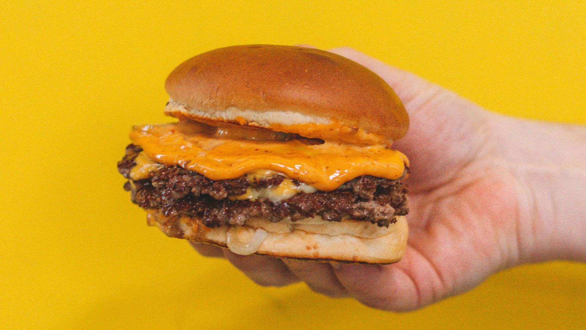 person holding burger with patty