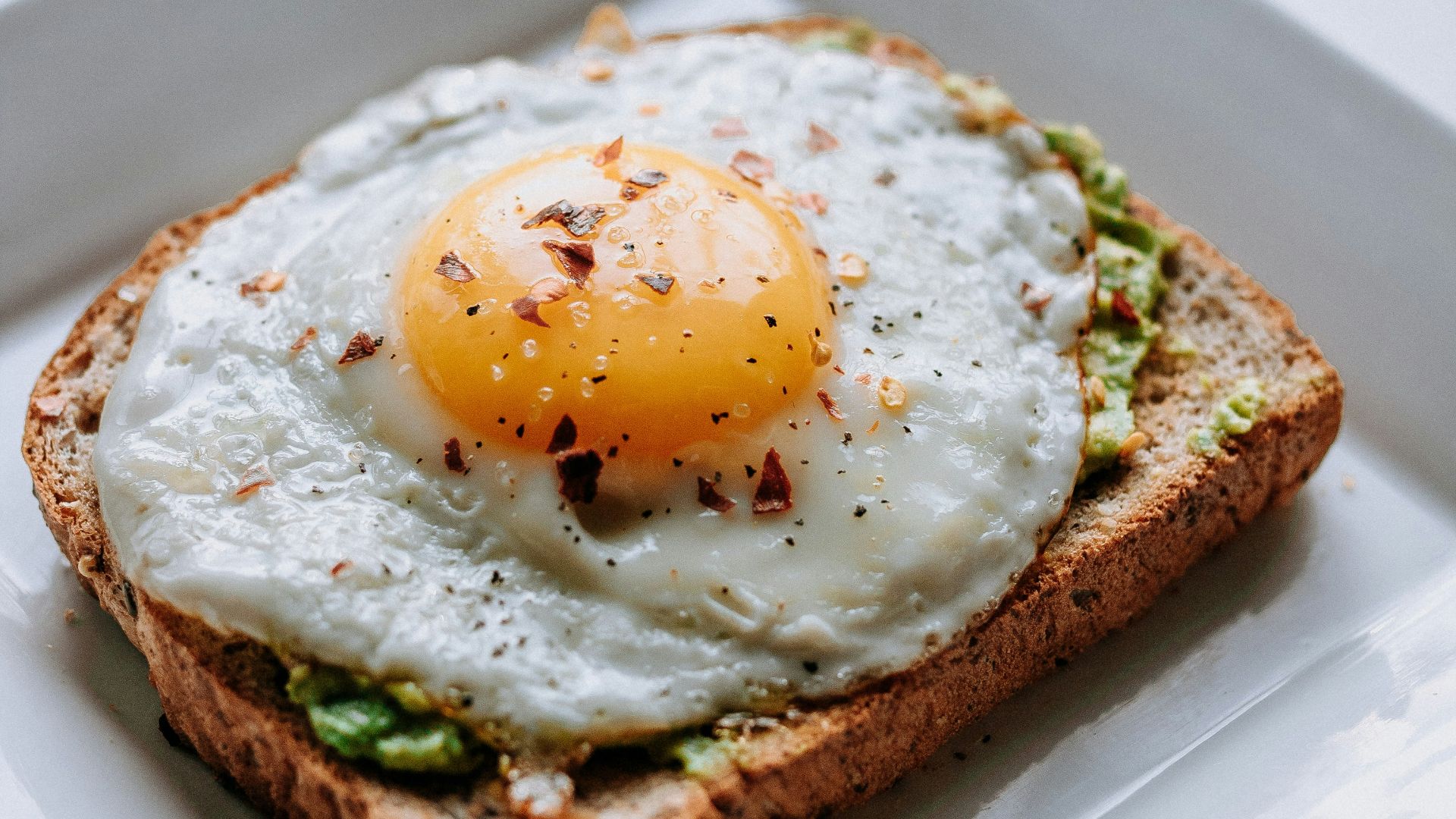 bread with sunny side-up egg served on white ceramic plate