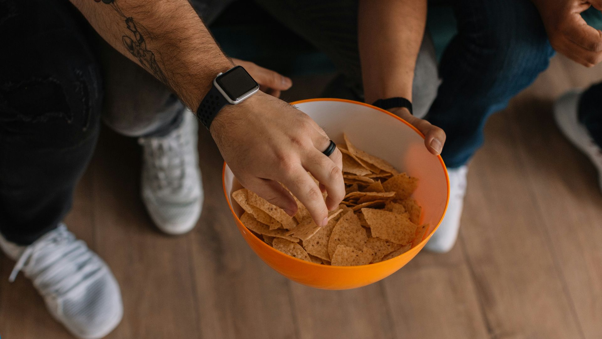 person holding orange bowl with potato chips