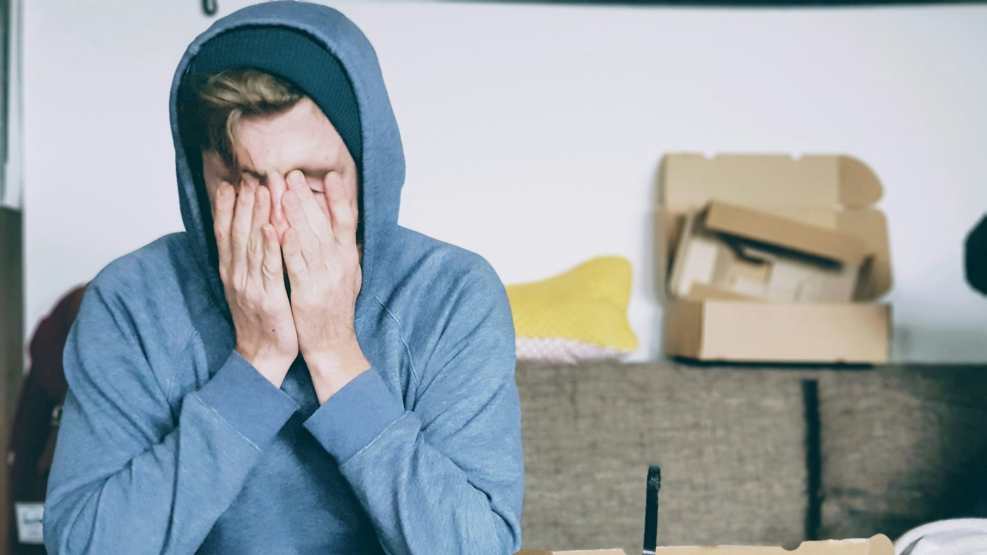 man covering face with both hands while sitting on bench