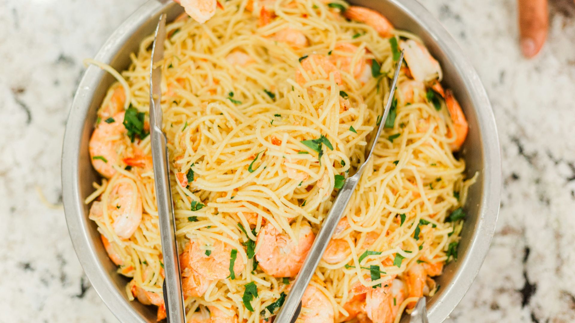 person holding stainless steel bowl with noodles