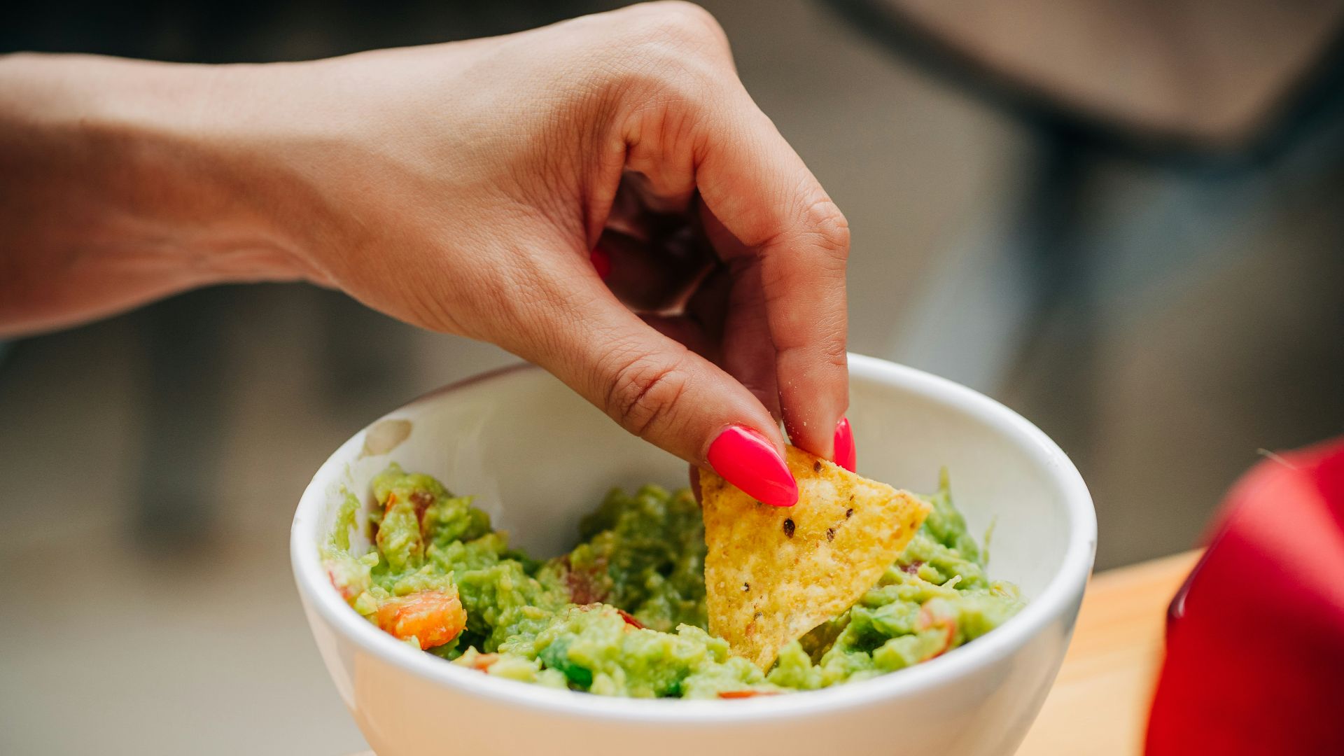 a person dipping a tortilla into a bowl of guacamole