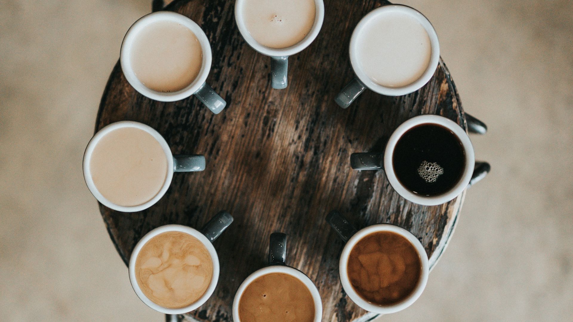flat lay photography of eight coffee latte in mugs on round table