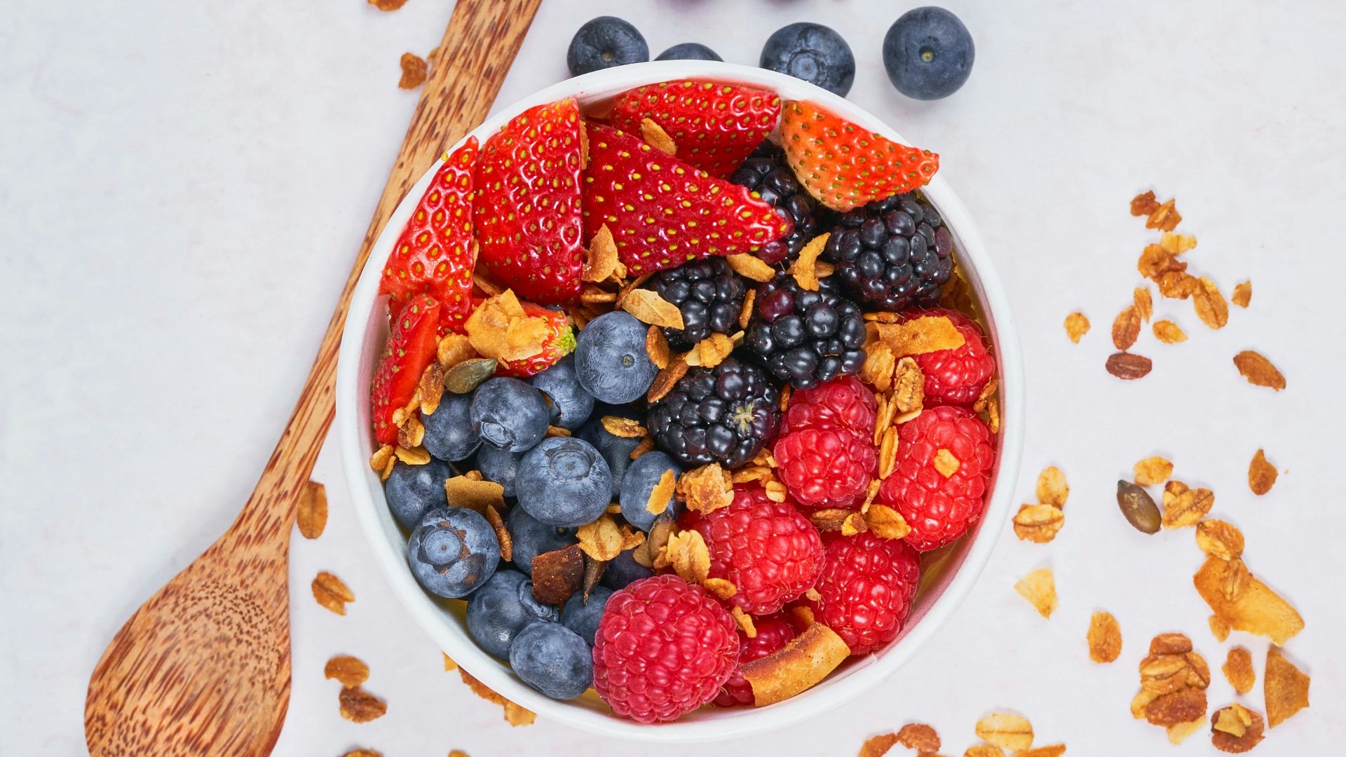 red strawberries and blue berries on white ceramic bowl