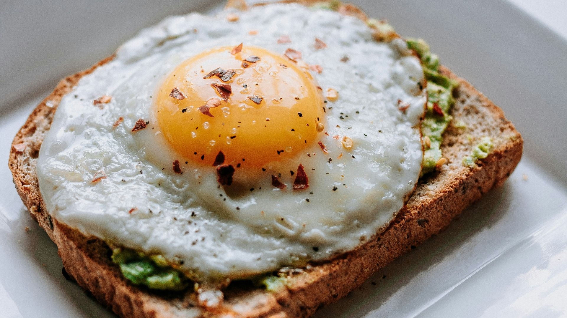 bread with sunny side-up egg served on white ceramic plate