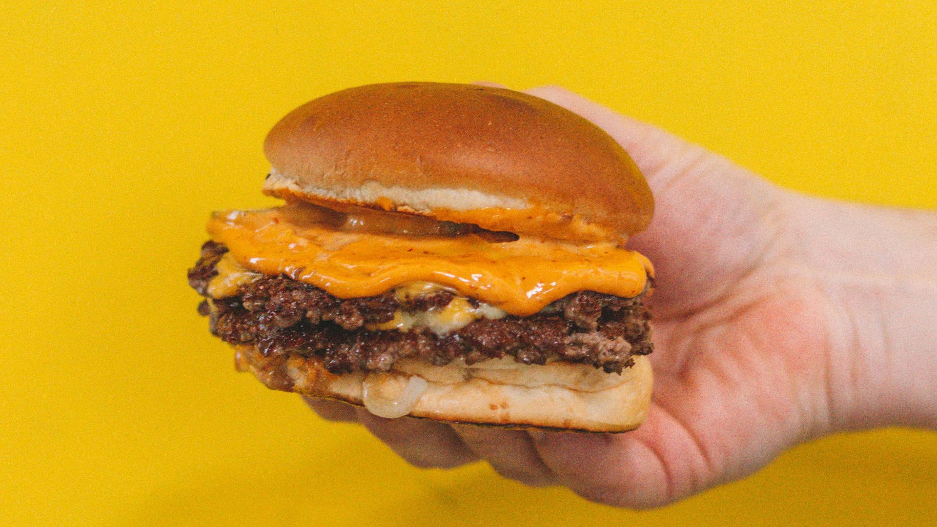 person holding burger with patty