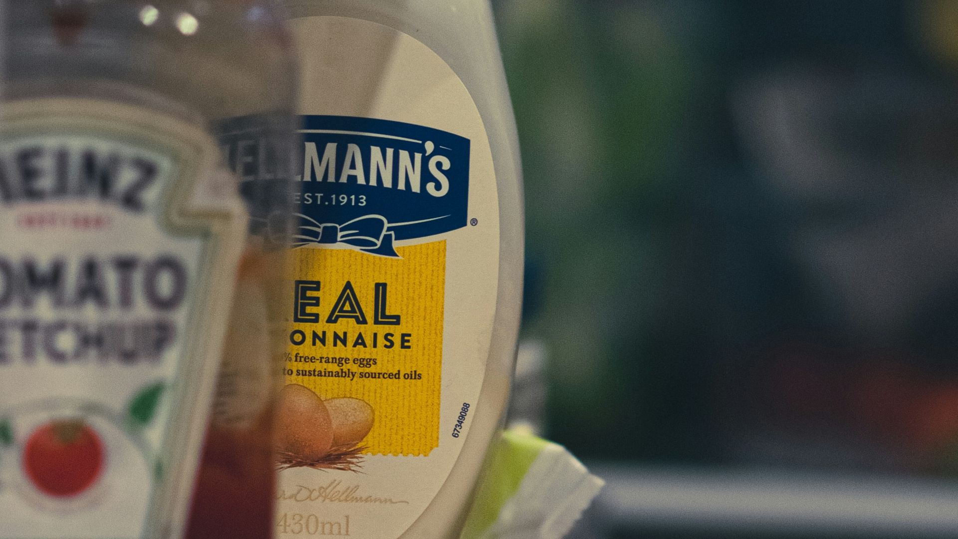 a container of mayonnaise and a bottle of ketchup on a shelf