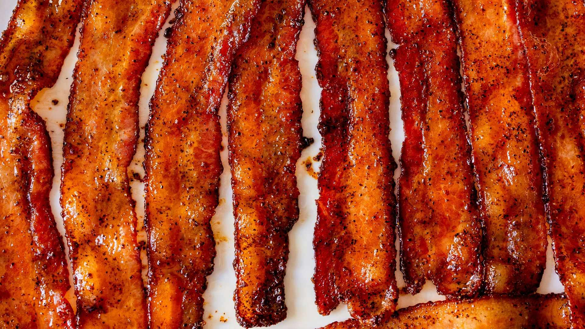 a white plate topped with bacon strips on top of a table