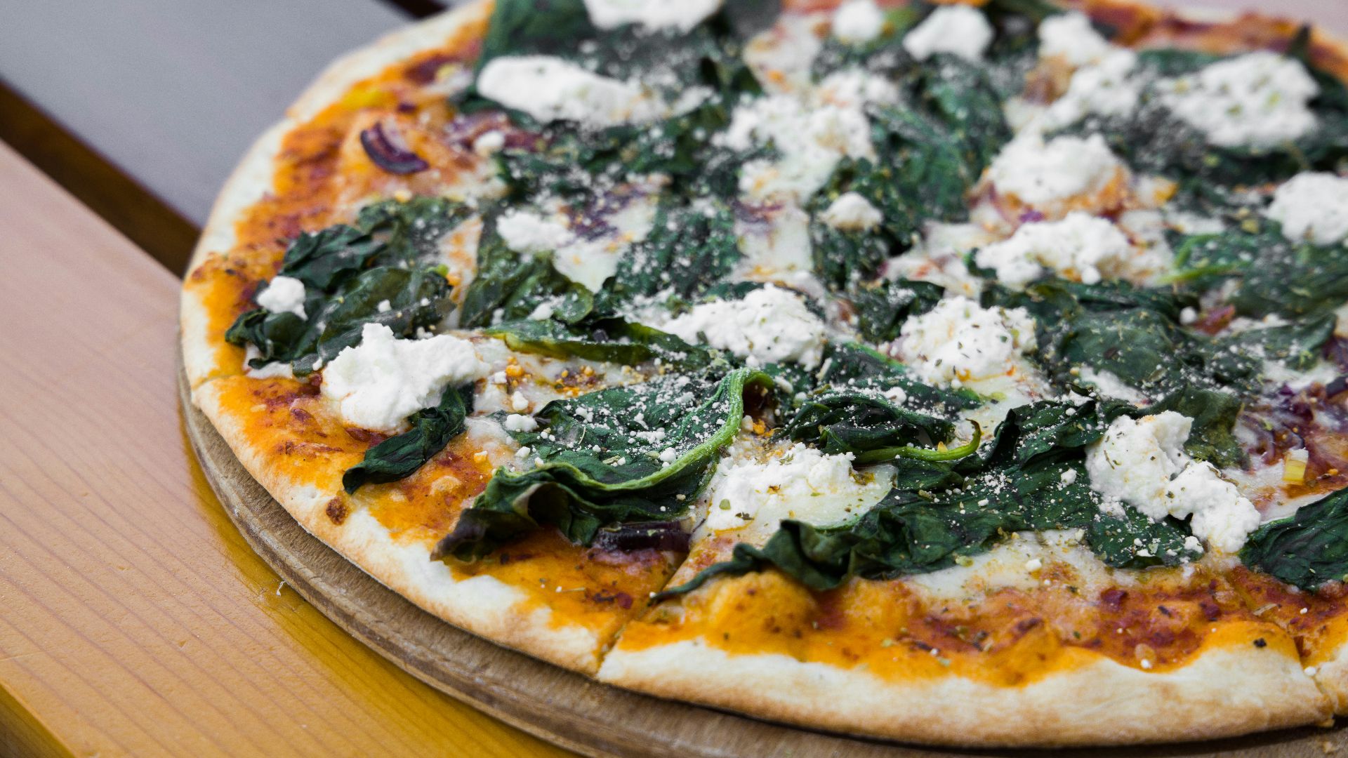 pizza with green leaves on brown wooden table
