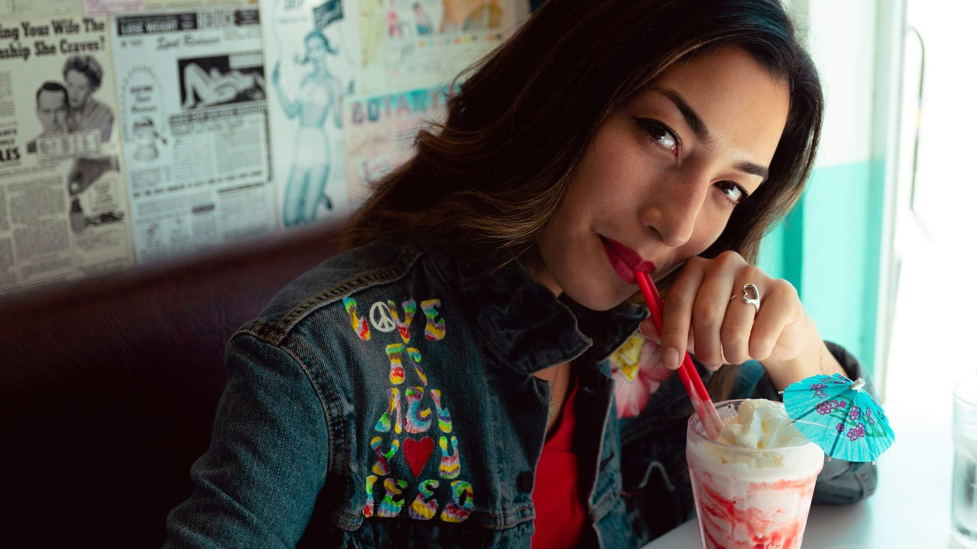 woman in red and blue jacket holding clear plastic cup