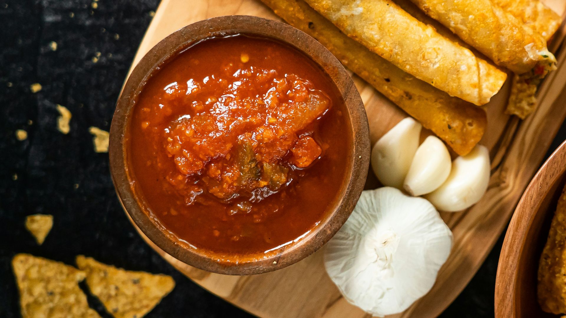 a wooden tray topped with chips and salsa