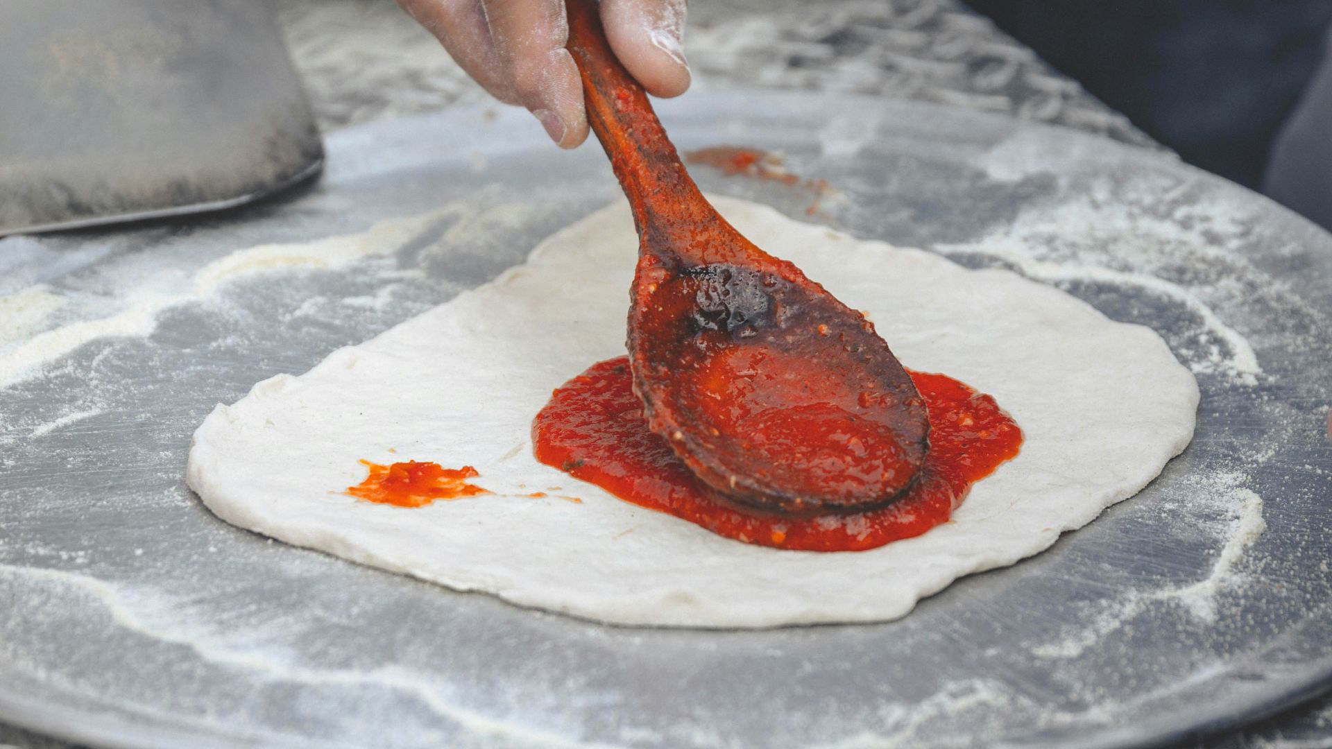 person holding brown wooden spoon with red powder