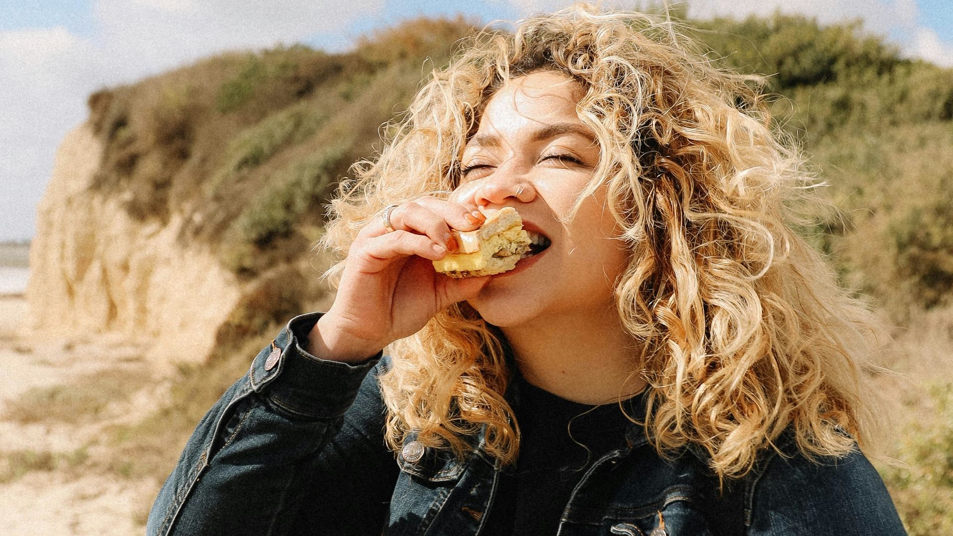 woman in black leather jacket standing on brown sand during daytime