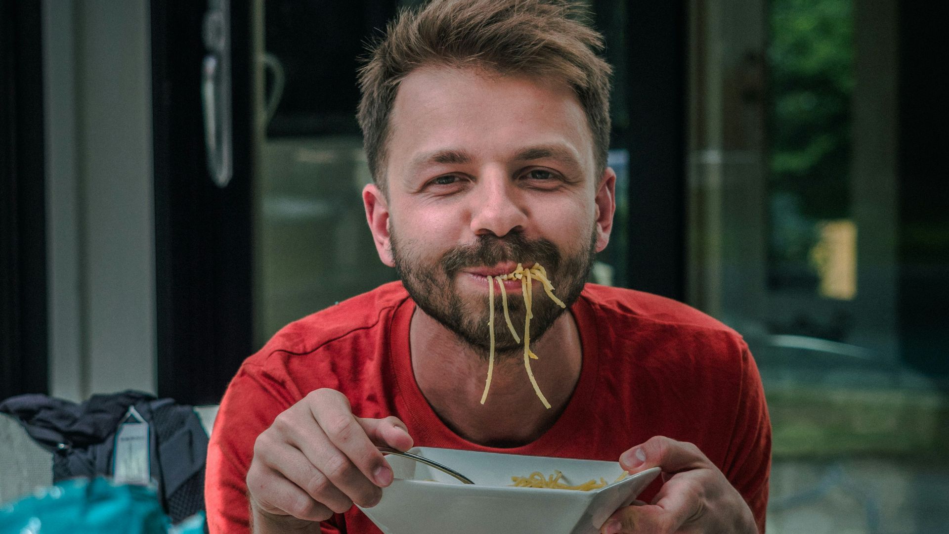 man in red crew neck t-shirt holding white and red labeled can
