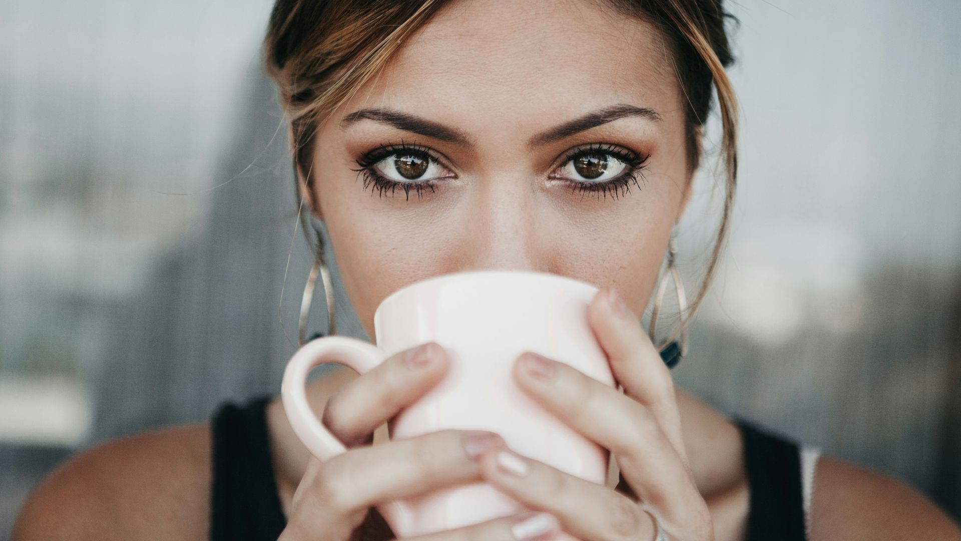 woman drinking from white coffee cup