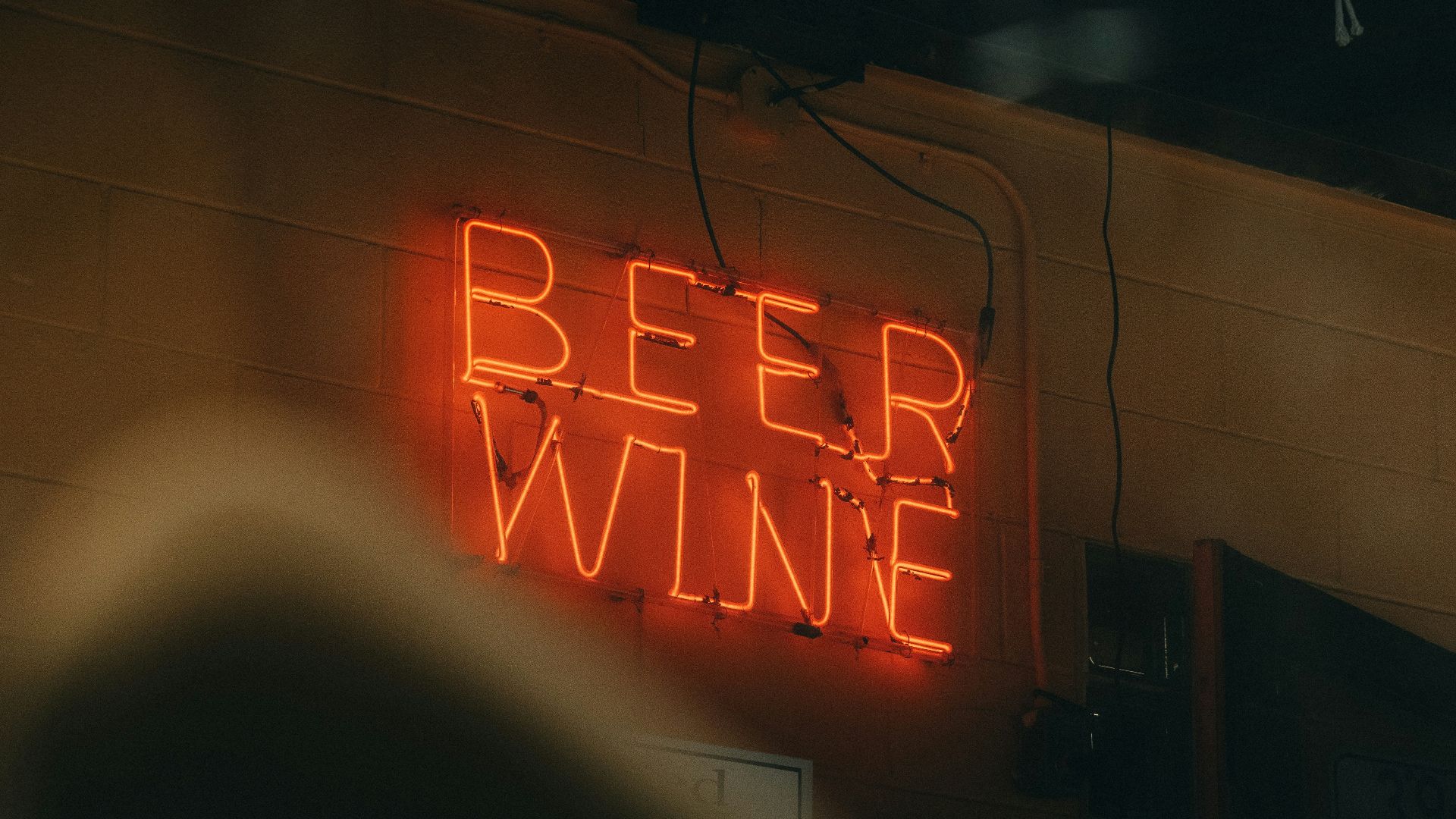 a neon sign that says beer wine on the side of a building