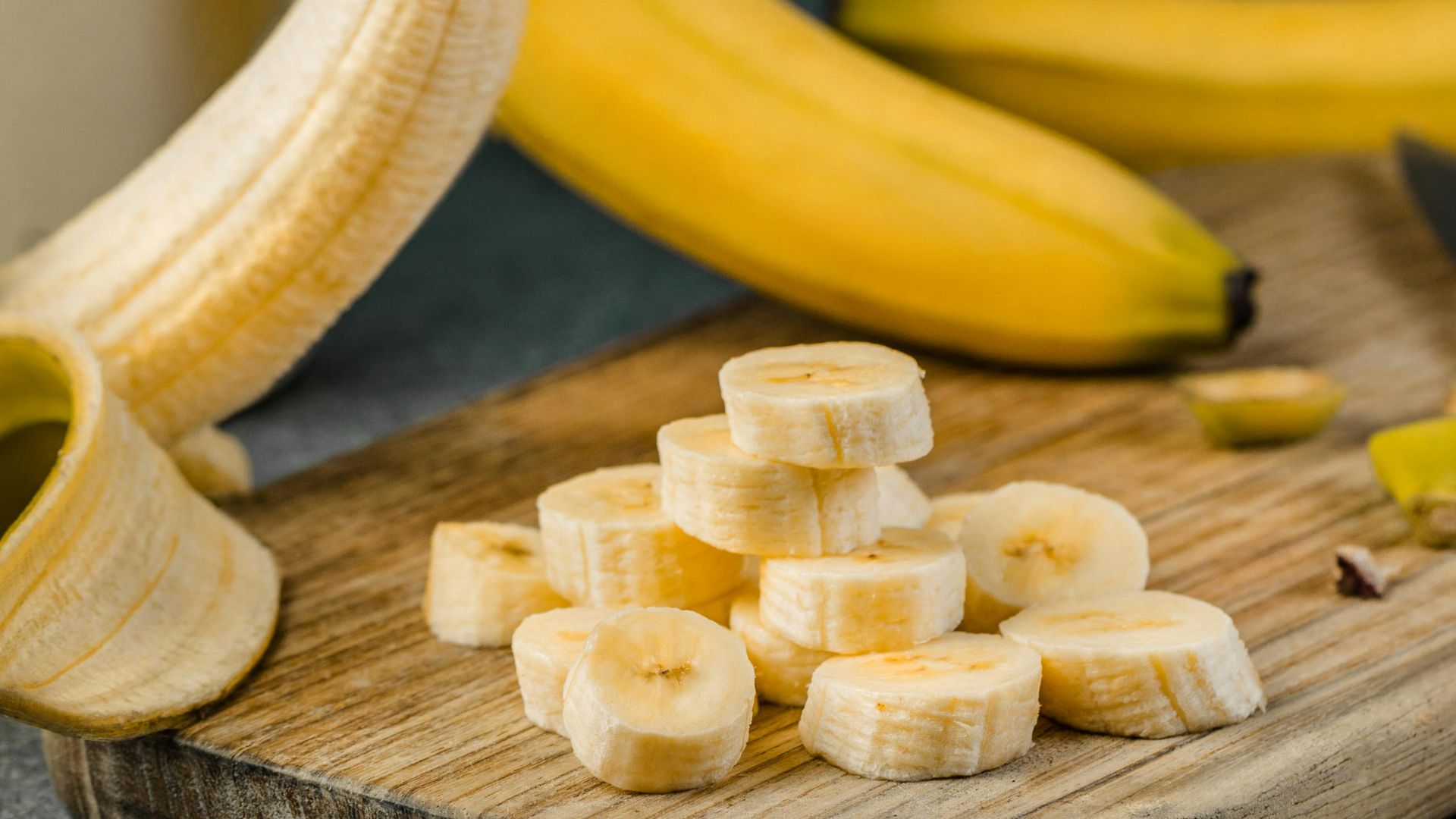 yellow banana fruit on brown wooden chopping board