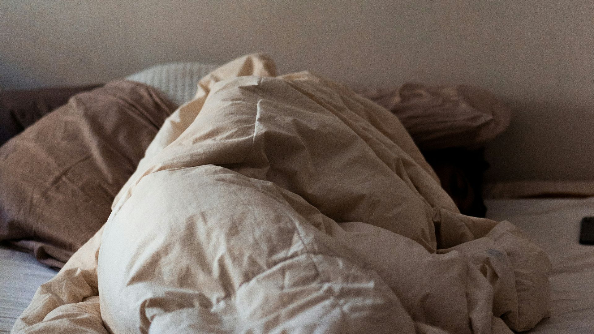 an unmade bed with a white comforter on top of it
